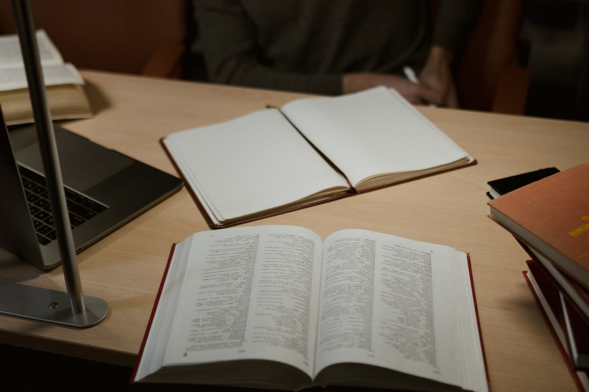Open books and a laptop on a wooden desk