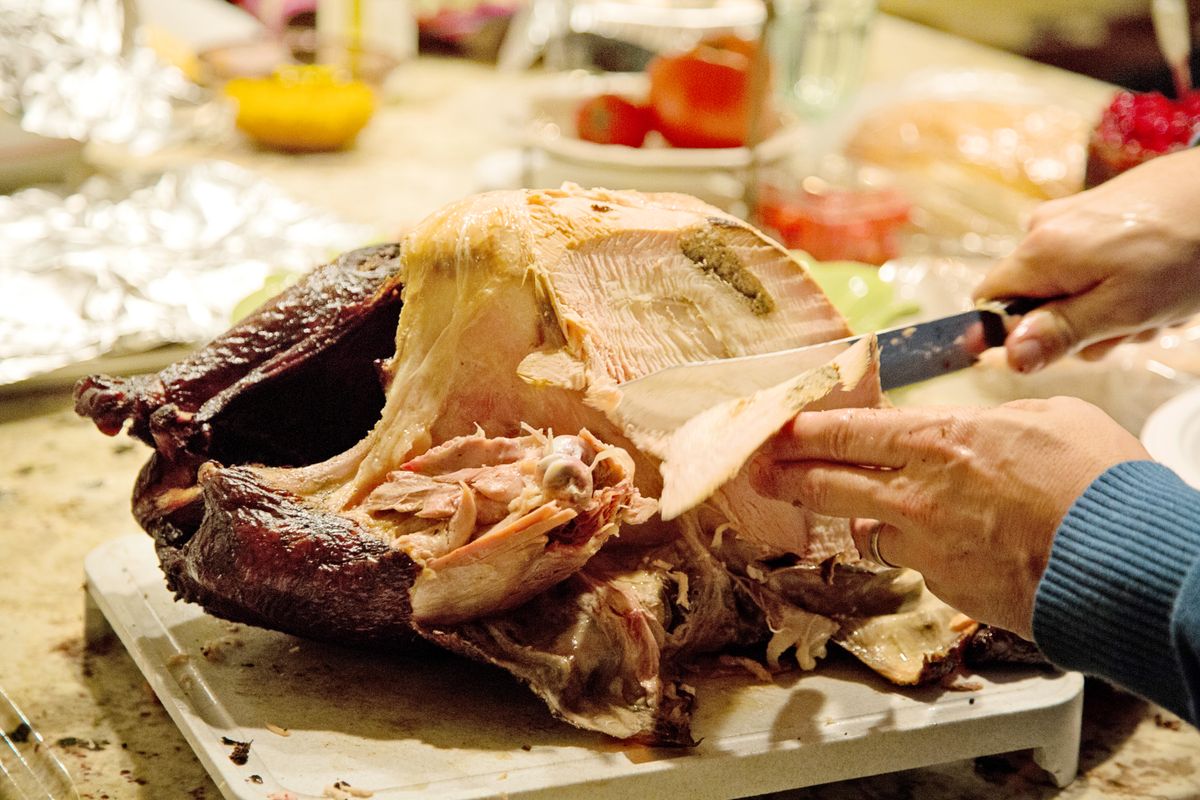 Hands carving a roasted bird on a kitchen counter