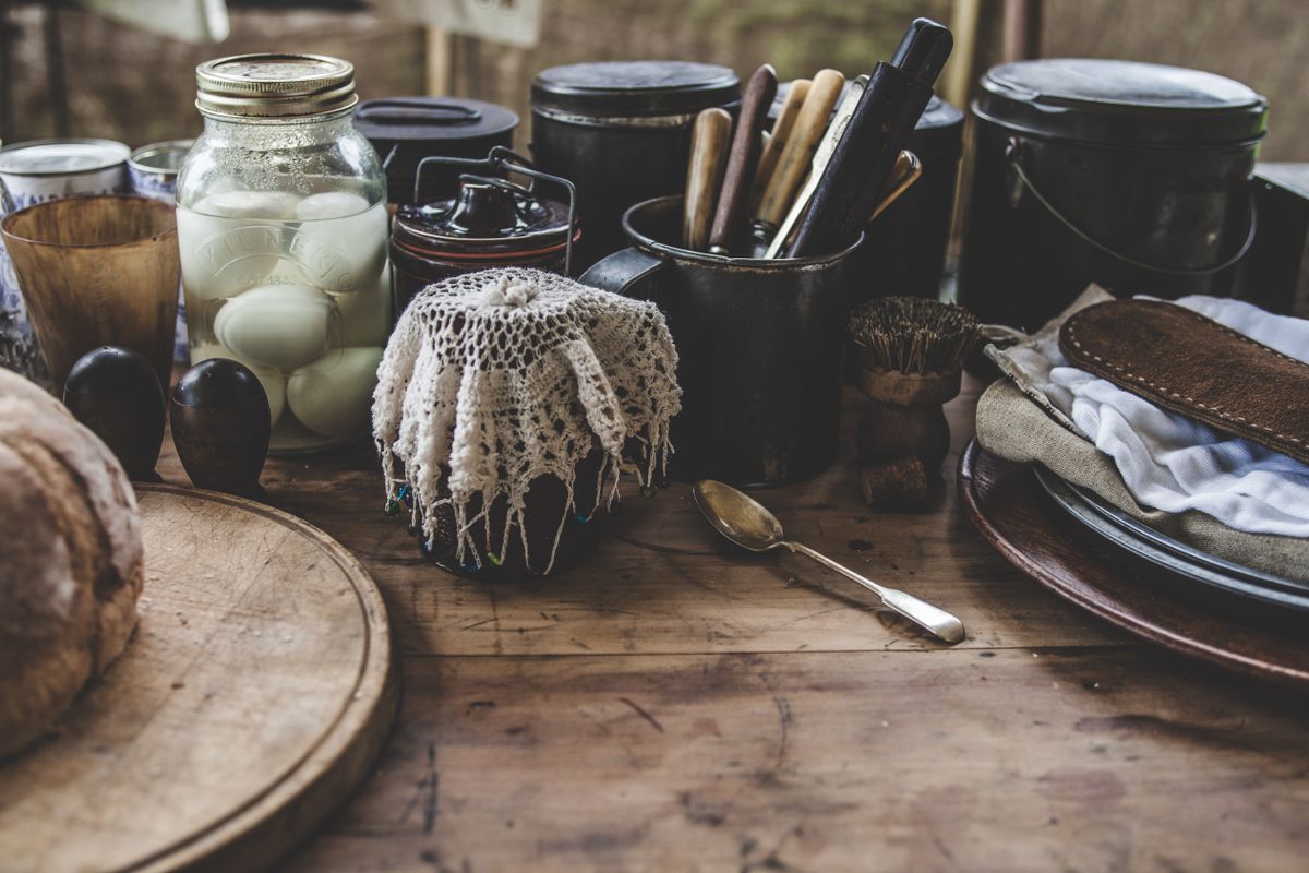 A jar of pickled eggs on a wooden table beside bread