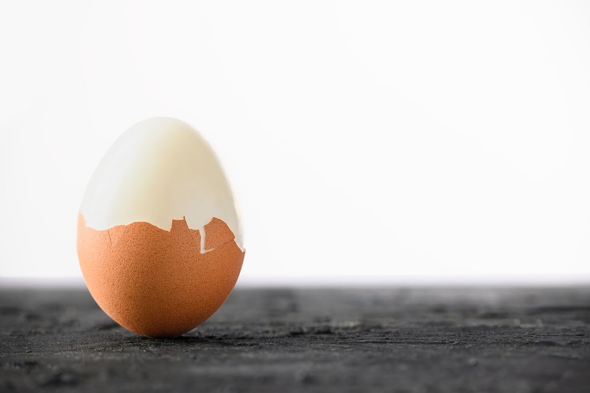 A boiled egg with its shell partly peeled away