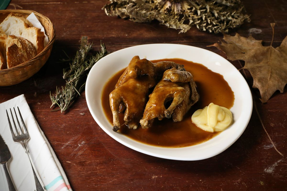 A roasted quail plated with gravy and mashed potato