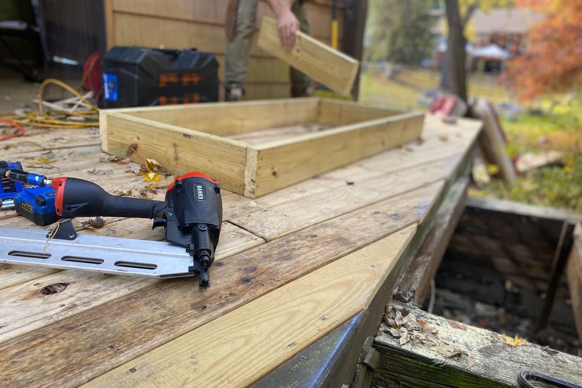 A wooden frame under construction with a nail gun resting on the deck